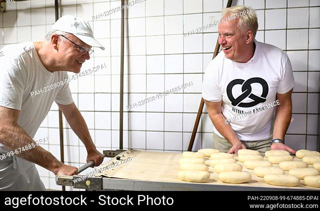 08 September 2022, Lower Saxony, Hanover: Stephan Weil (l, SPD), Minister President of Lower Saxony, puts rolls into an oven early this morning in the bakery of...