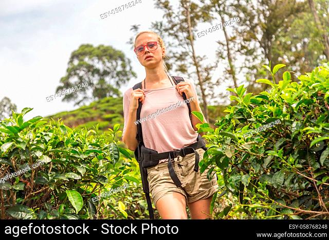 Active caucasian blonde woman enjoing fresh air and pristine nature while tracking among tea plantaitons near Ella, Sri Lanka