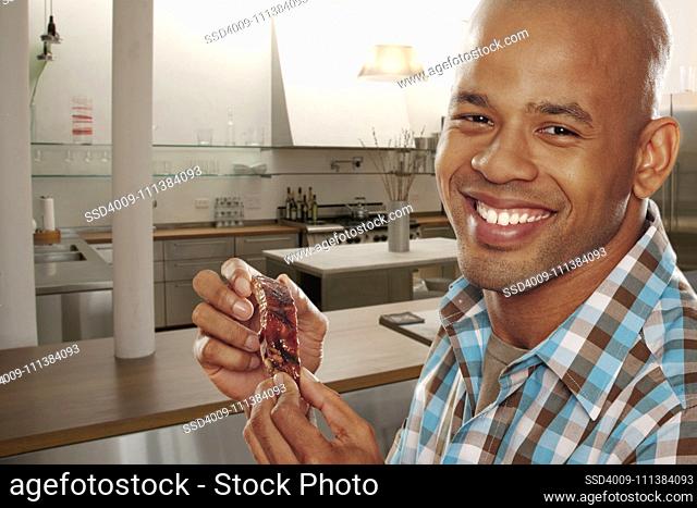 Black man eating ribs in kitchen