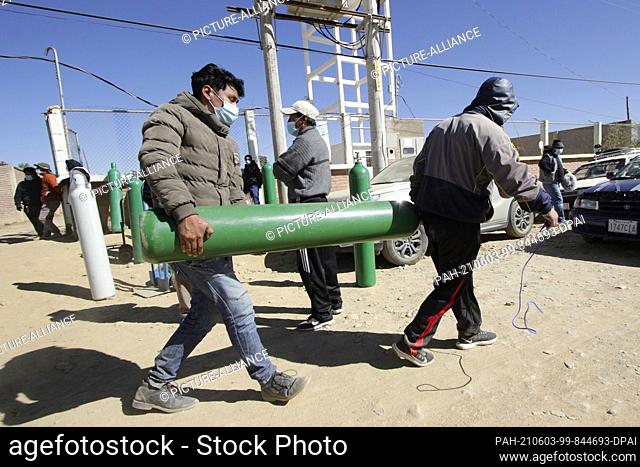 02 June 2021, Bolivia, Cochabamba: Two members of a family pick up their oxygen tank and leave the line at the medical oxygen generation facility when they...