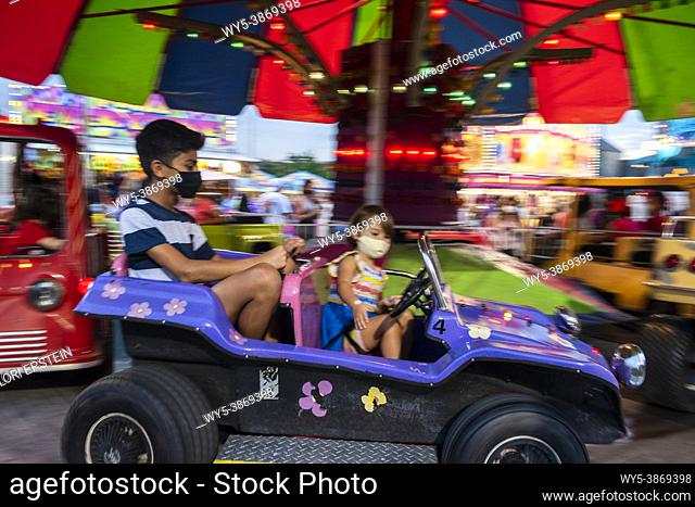 A 12-year-old boy rides a kiddie buggy ride with his little cousin at a county fair in Arlington, Virginia