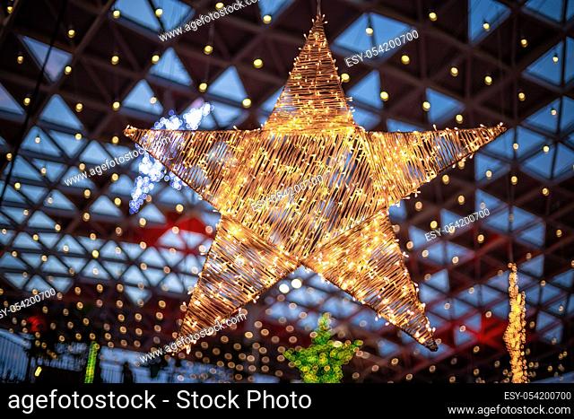 A giant golden star shaped decoration made from little LED lights and thread hanging by the ceiling. selective focus