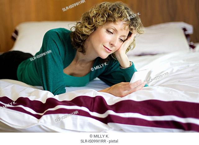 Mid adult woman using cellphone in bedroom