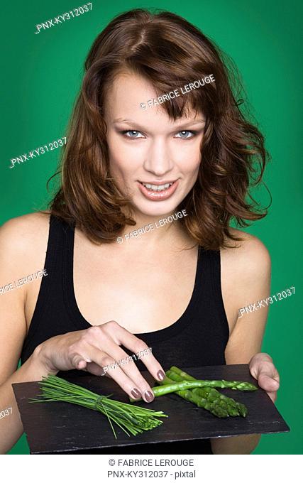 Young woman holding tray of asparagus and chives
