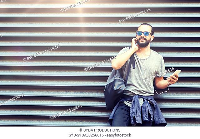 man with earphones and smartphone on city street