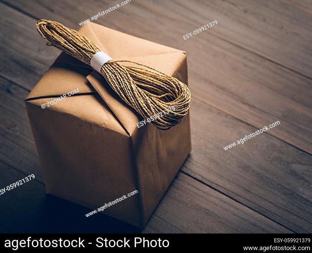brown cube box with a bundle of string on, isolated on wooden table