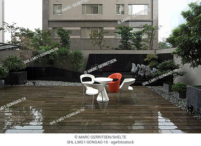 Modern deck furniture in rain on wooden deck