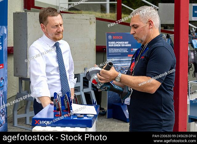 30 June 2023, Saxony, Sebnitz: Martin Thiel (r), Head of Quality at Bosch Power Tools GmbH, shows Michael Kretschmer (CDU), Minister President of Saxony