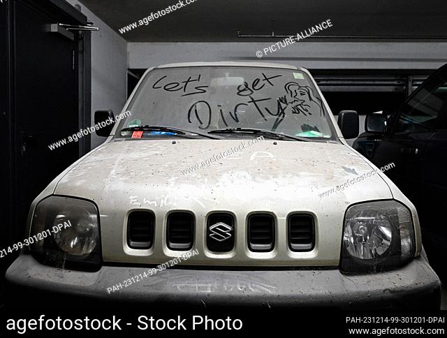 14 December 2023, Brandenburg, Potsdam: A very dirty ""Suzuki"" car without license plates with the words ""Let's get dirty"" is parked in the parking garage at...