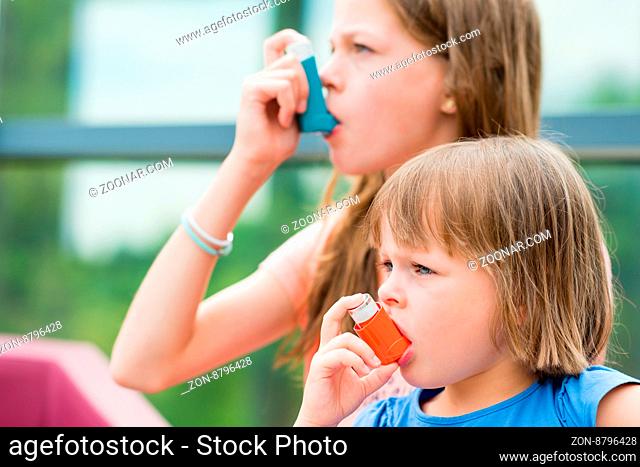 Girls having asthma using asthma inhaler for being healthy - shallow depth of field