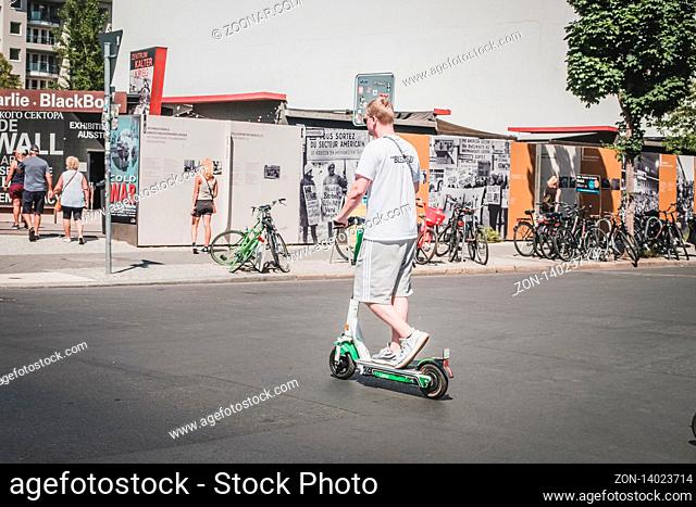 Berlin, Germany - June, 2019: Young man riding electric scooter , escooter or e-scooter on street in Berlin, Germany