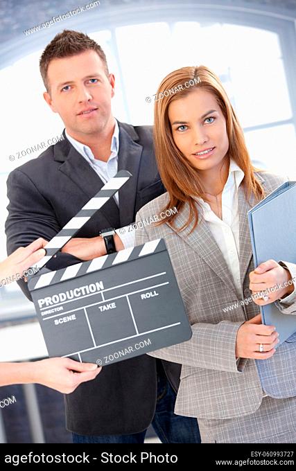Attractive businesspeople with clapper board, during shooting a film, smiling