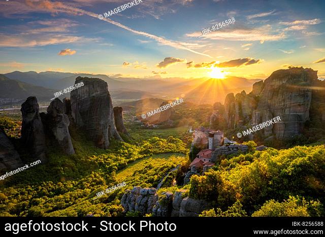 Sunset over monastery of Rousanou and Monastery of St. Nicholas Anapavsa in famous greek tourist destination Meteora in Greece on sunset with sun rays and lens...