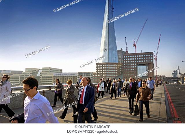 Commuters walking to work over London Bridge with the Shard building in the background