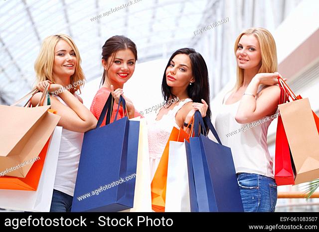 Young beautiful happy women showing shopping bags in mall and smiling