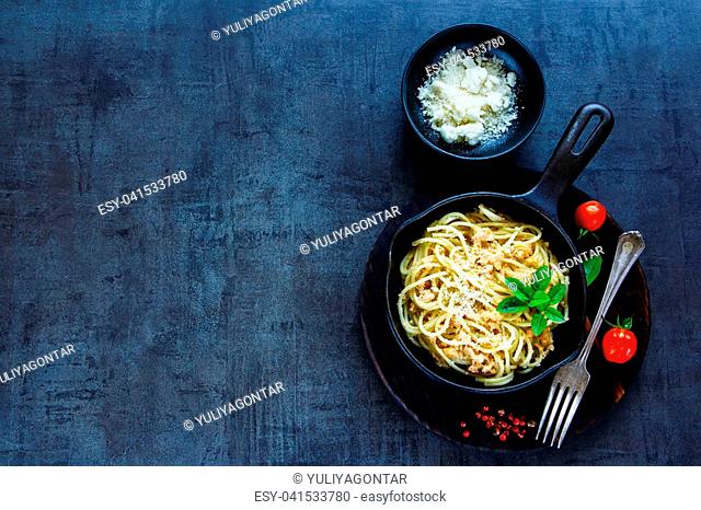 Top view of pasta with creamy crab sauce in black cast iron pan on vintage stone background. Top view. Copy space
