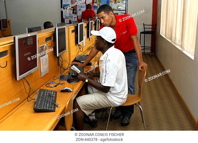 Ein Mitarbeiter des Internetcafé Busyinternet hilft einem Kunden bei der Arbeit am Komputer, Accra, Ghana / Qualified staff of the Internetcafé Busyinternet...