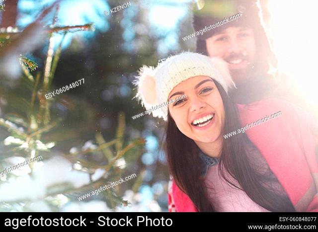 Closeup of happy couple smiling and hugging in winter forest