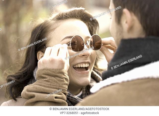 boyfriend dressing buoyant teenage girlfriend with reversed sunglasses, wrong way round, couple in Cottbus, Brandenburg, Germany