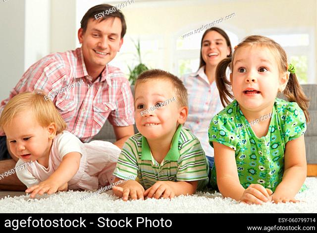 Family at home: happy children with their parents lying on floor making faces