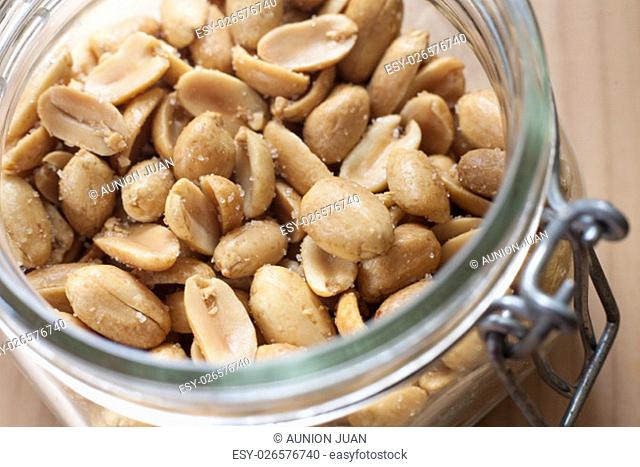 Open canning jar with fried salty peanuts. Selective focus. High angle view