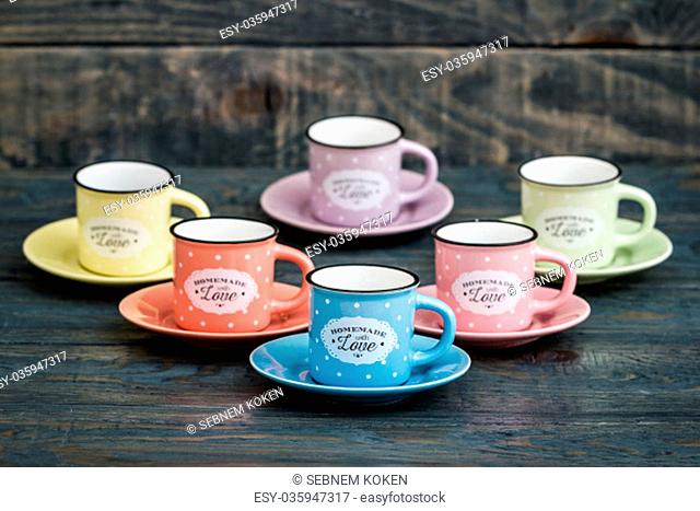 Colorful ceramic mugs with enamel look on blue wooden background