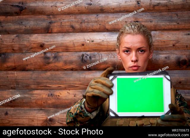 woman soldier using tablet computer against old wooden wall in camp