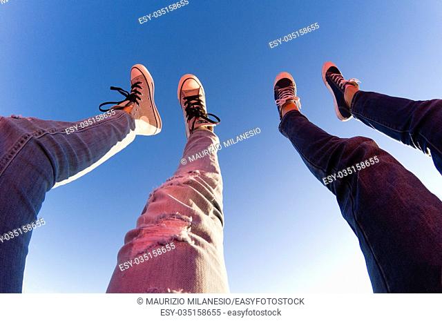 Young couple lifts their legs towards clear blue sky