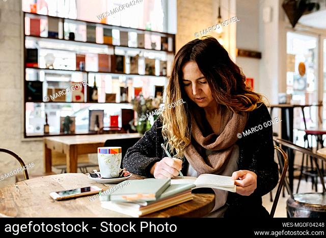 Woman writing in notebook in coffee shop