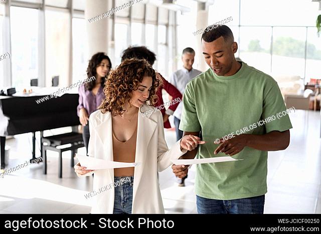 Smiling businesswoman with businessman discussing document at office