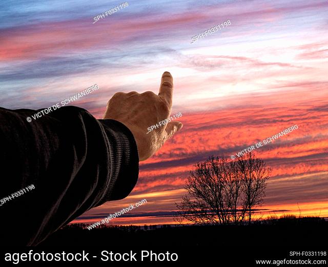 Hand pointing to the sunset