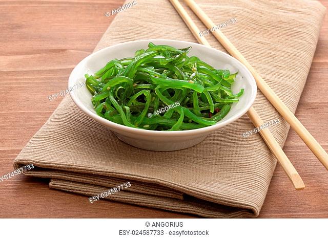 White bowl with chuka seaweed on the napkin with wooden chopsticks