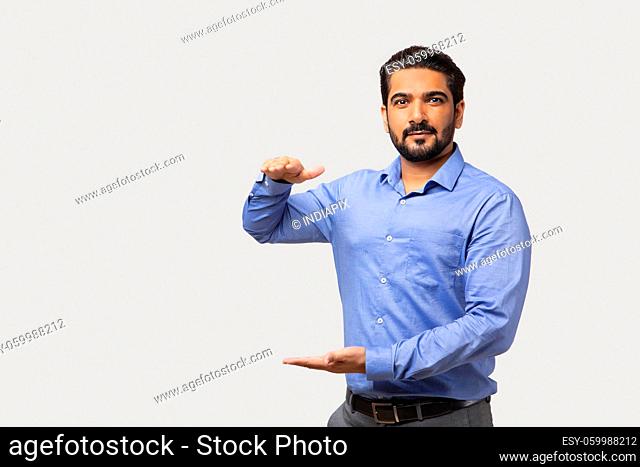 Portrait of man in formal clothing gesturing sign of size with both hands