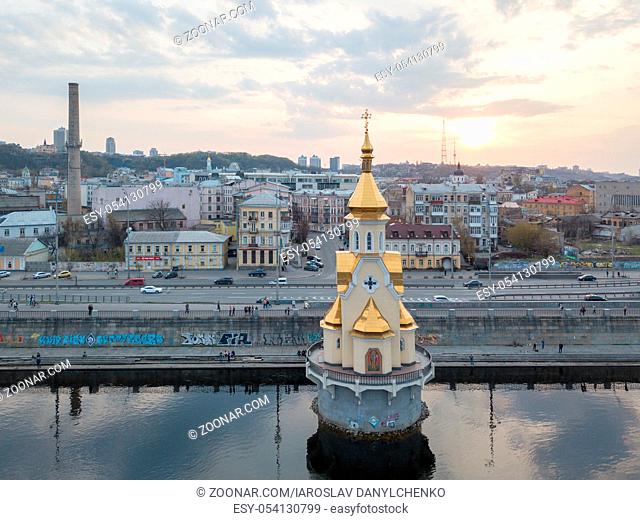 View of the church of St. Nicholas on the water and a panoramic view of the cityscape of Kiev at sunset, Ukraine. Drone photo