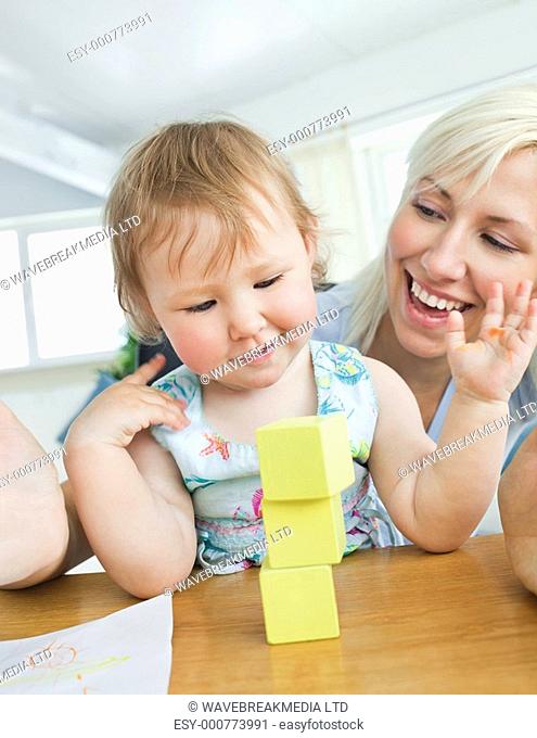 Smiling mother playing with her daughter in living room