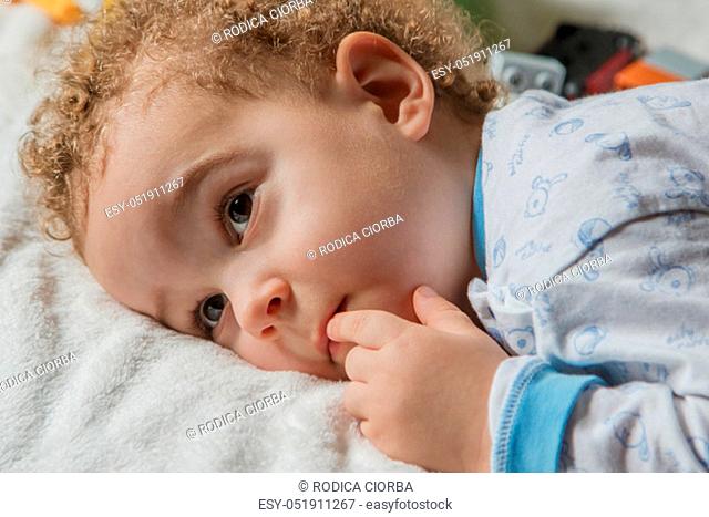 Adorable two years old kid in soft pyjamas with blue and withe colours in sunny kids room. Child's sleep concept, soft focus