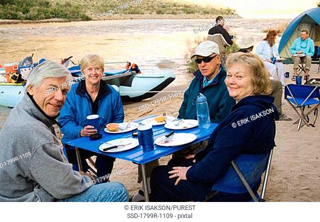 Two senior couples sitting at a breakfast table along a river, Green River, Moab, Utah, USA
