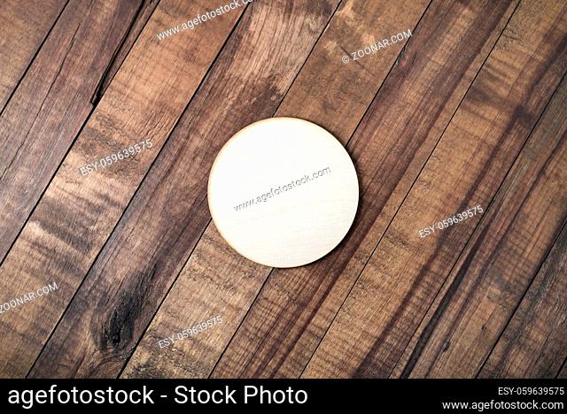 Blank wooden beer coaster on wood table background. Flat lay