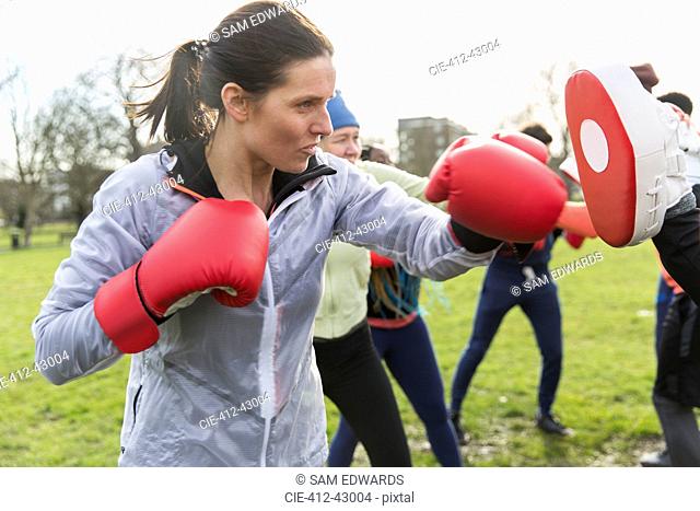 Determined, tough woman boxing in park