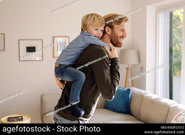 Happy father carrying son piggyback at home