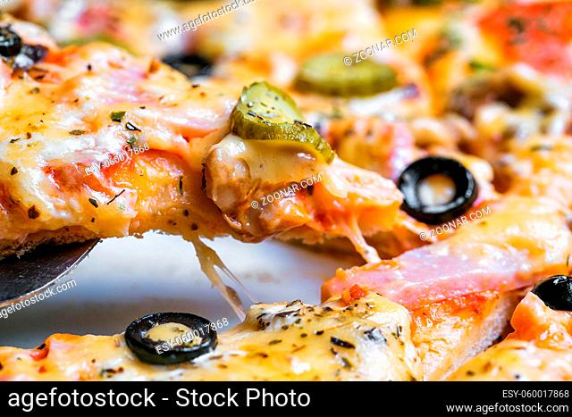 pizza with ham, by cut to pieces on a metal table. selective focus on the filling close-up