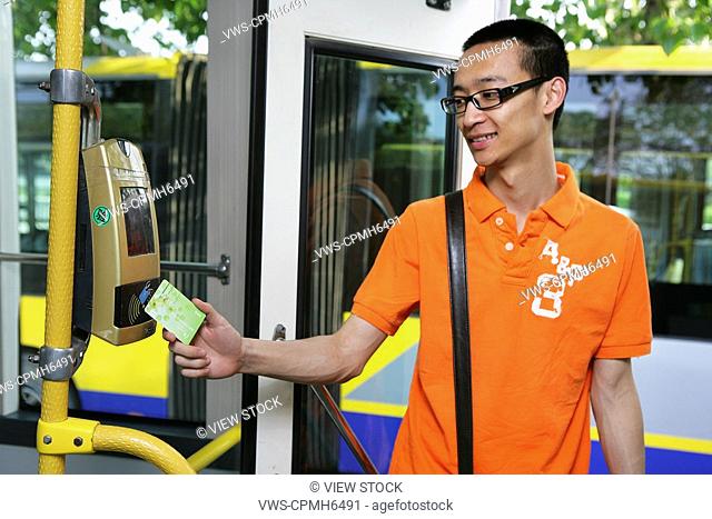 a chinese young man paying bus fare with a bus card