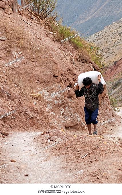 worker hauling bags of salt at Salinas De Maras, Peru, Cusco