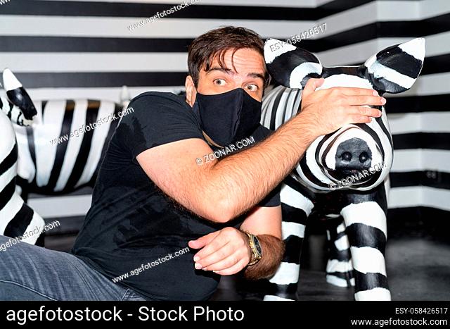 Portrait of Persian man with mask for protection from corona virus outbreak inside room with black and white theme