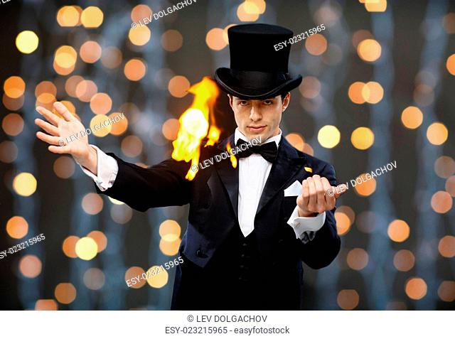 magic, performance, circus, people and show concept - magician in top hat showing trick over nigh lights background