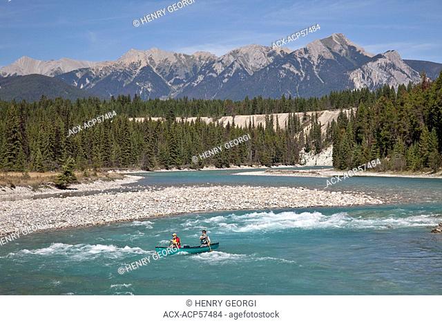 Couple paddle canoe through rapids on Kootenay River, Kootenay National Park, BC, Canada
