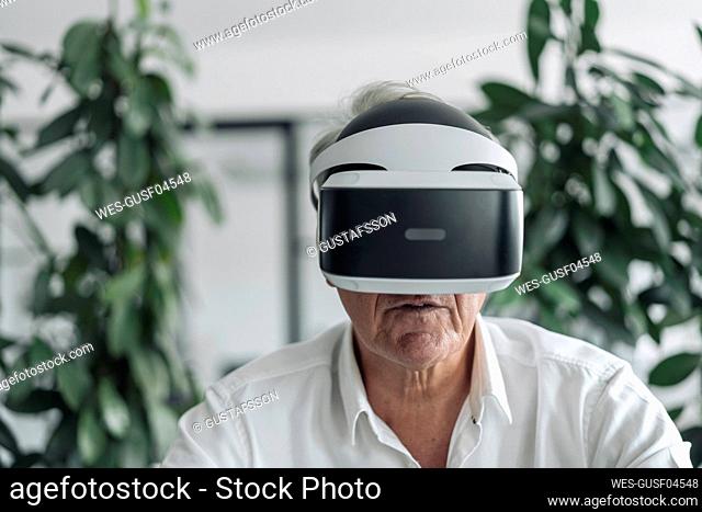 Businessman wearing virtual reality eyeglasses while sitting at office