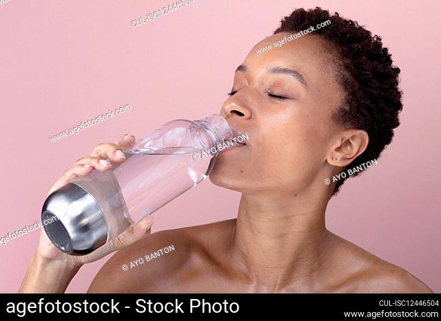 Studio shot of woman drinking water from bottle