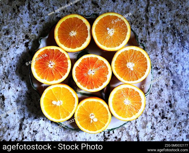 Juicy halves of four oranges arranged in a circle on an ornate platter. Design in eight perfect semi-circles