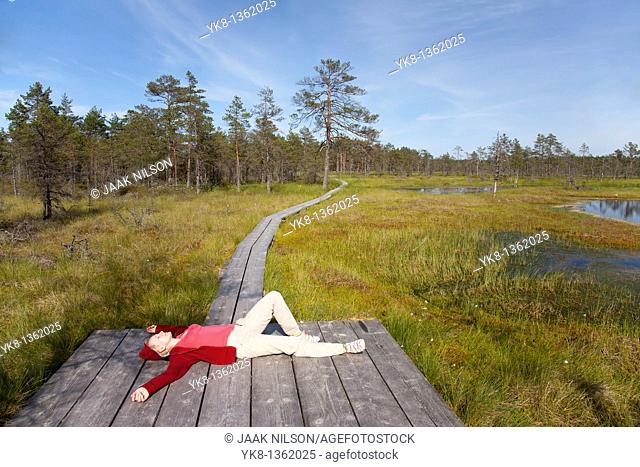 Young Woman Lying on Wooden Boardwalk in Viru Bog, Lääne-Viru County, Estonia, Europe